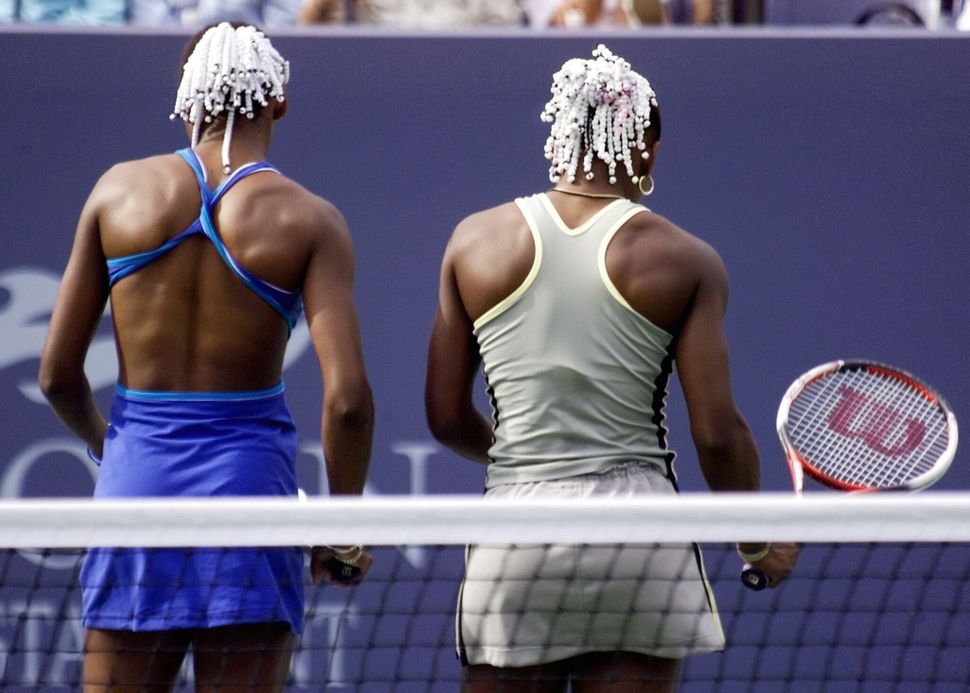 Venus (left) and Serena Wiliams talk strategy during a match at the U.S. Open in Flushing Meadows, New York, on Sept. 2, 1999