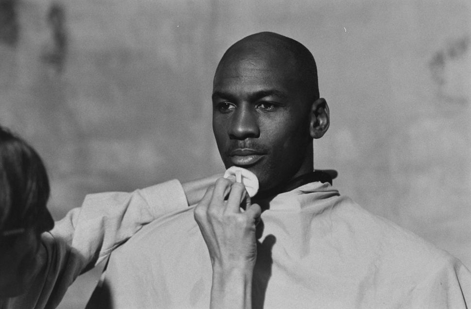 Michael Jordan, preparing to model a line of formal wear, sits while makeup artist Marty Thompson dusts his chin.