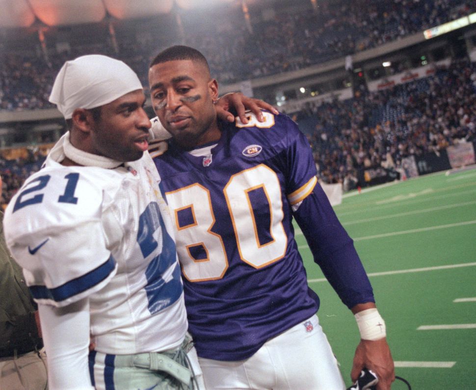 Sanders of the Dallas Cowboys (left) and Minnesota Vikings wide receiver Cris Carter greet each other following a Vikings pla