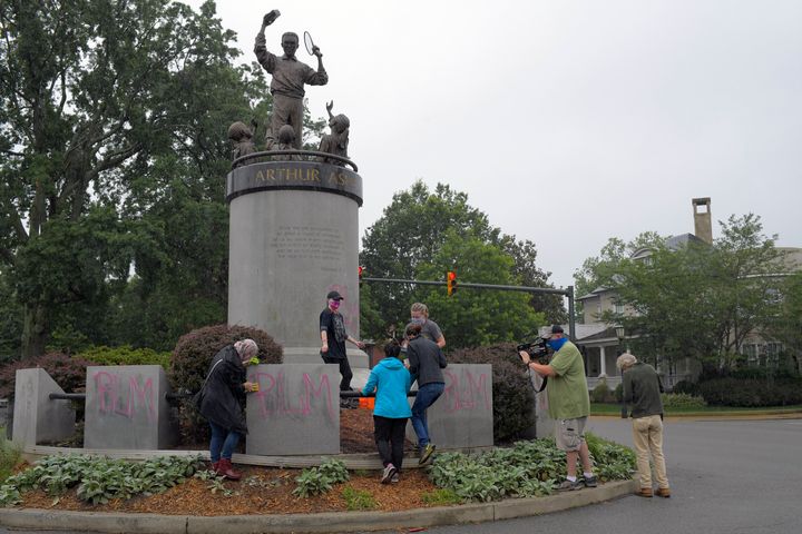 Volunteers clean off spray-painted graffiti on the Arthur Ashe memorial in Richmond, Virginia.