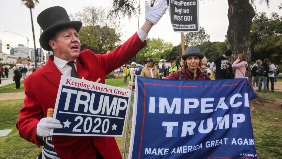 Gregg Donovan, left, supporter of President Donald Trump holds a sign during a rally against a visit by President Donald Trump, March 13, 2018.