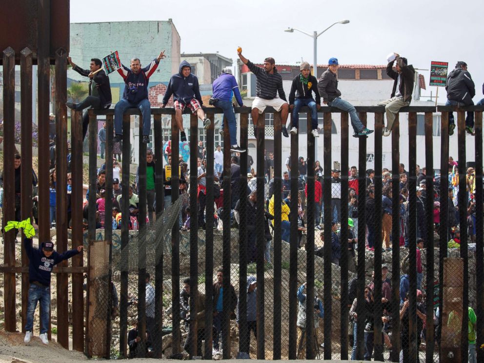 PHOTO: People in Mexico climb the border wall fence as a caravan of migrants and supporters reached the United States-Mexico border near San Diego, Calif., April 29, 2018. 