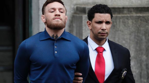 Ultimate fighting star Conor McGregor, left, is led by an official to an unmarked vehicle while leaving the 78th Precinct of the New York Police Department, Friday, April 6, 2018, in the Brooklyn borough of New York. McGregor is facing criminal charges in the wake of a backstage melee he allegedly instigated that has forced the removal of three fights from UFC's biggest card of the year. Video footage appears to show the promotion's most bankable star throwing a hand truck at a bus full of fighters after a Thursday news conference for UFC 223 at Brooklyn's Barclays Center. (AP Photo/Julio Cortez)