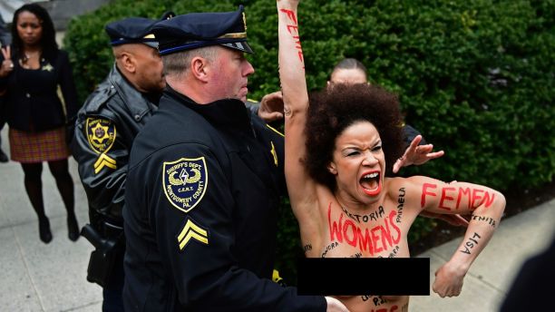 EDS NOTE: NUDITY - A protester is detained as Bill Cosby arrives for his sexual assault trial at the Montgomery County Courthouse, Monday, April 9, 2018, in Norristown, Pa. (AP Photo/Corey Perrine)