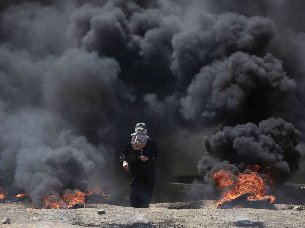 PHOTO: A Palestinian woman walks through black smoke from burning tires during a protest on the Gaza Strips border with Israel, May 14, 2018.