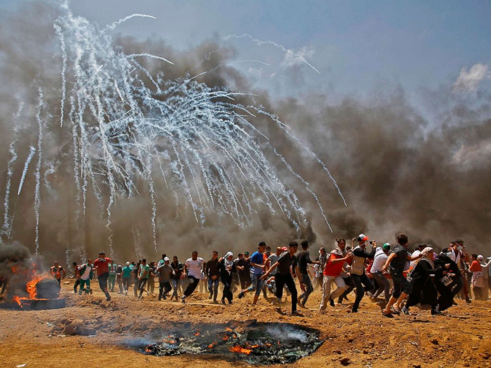PHOTO: Palestinians run for cover from tear gas during clashes with Israeli security forces near the border between Israel and the Gaza Strip, east of Jabalia, May 14, 2018.