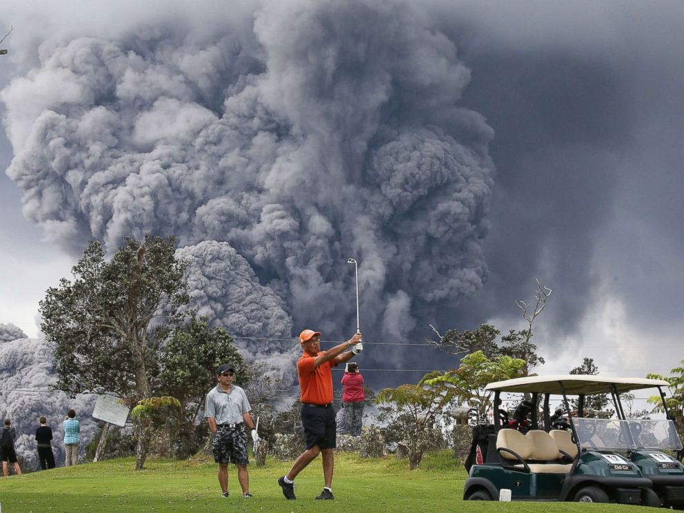 PHOTO: People play golf as an ash plume rises in the distance from the Kilauea volcano on Hawaiis Big Island, May 15, 2018, in Hawaii Volcanoes National Park, Hawaii. 