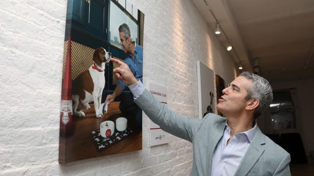 A touching moment; Andy Cohen reacts to a photo at Gallery 28 by Purina ONEÂ®, which celebrates the brandâs ONE Difference Campaign on Tuesday, May 22, 2018 in New York City. The gallery features never-before-seen photos of Andy and Wacha in their home. Purina ONE is donating $5, up to $28,000, to the Petfinder Foundation for every person who signs up for the Purina ONE 28-Day Challenge between May 22 and June 30 to help more dogs, like Wacha, find their forever homes. To learn more, visit www.purinaone.com/makeonedifference.   (Photo by Amy Sussman/Invision for Purina ONE/AP Images)
