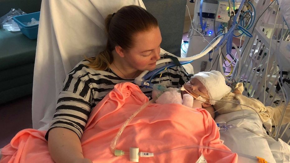 Baby McKenna Hovenga is held in the arms of her mother Kassy on Mother's Day. The infant is showing signs of improvement after an overthrown softball hit her head at her father's game earlier this month.