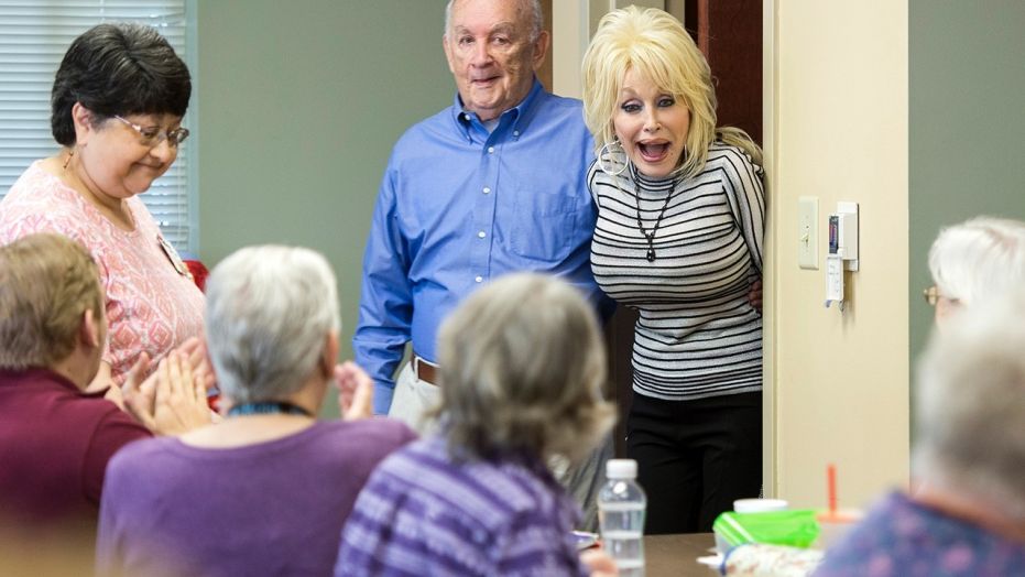 Country music superstar Dolly Parton, back right, surprises a quilting class at the renamed My People Senior Activity Center in Sevierville, Tenn., Monday, May 7, 2018. Parton came for a dedication ceremony Monday to rename the facility in honor of her parents, Robert and Avie Lee Parton.