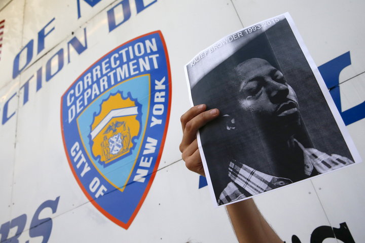 A demonstrator holds a photo of Kalief Browder during a candlelight vigil outside the entrance to the Rikers Island correctio