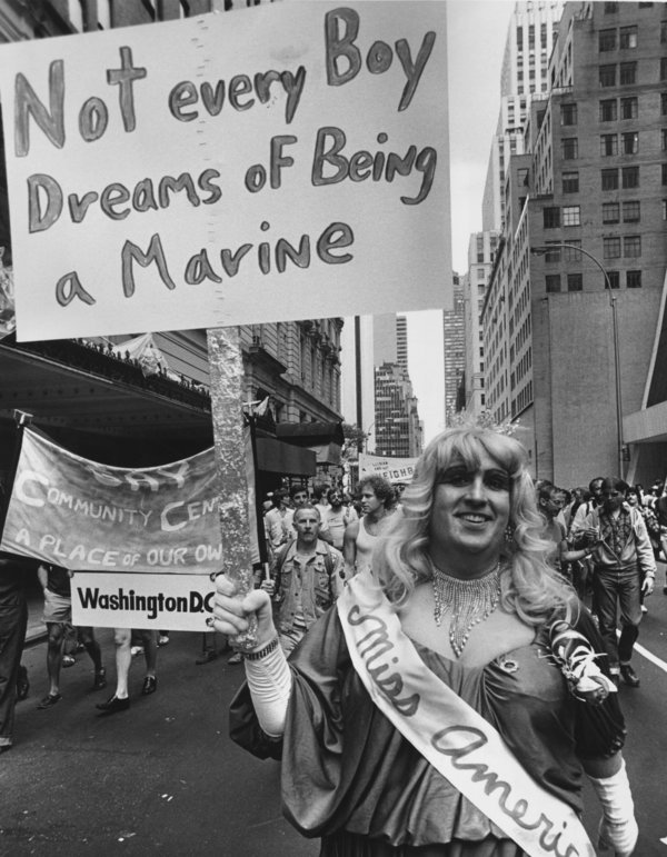 A gay rights protester in drag with a banner declaring 'Not Every Boy Dreans Of Being A Marine' during a gay rights march up 