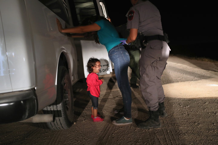 A 2-year-old Honduran girl cries as a Border Patrol agent searches her mother near the border between the U.S. and Mexico.