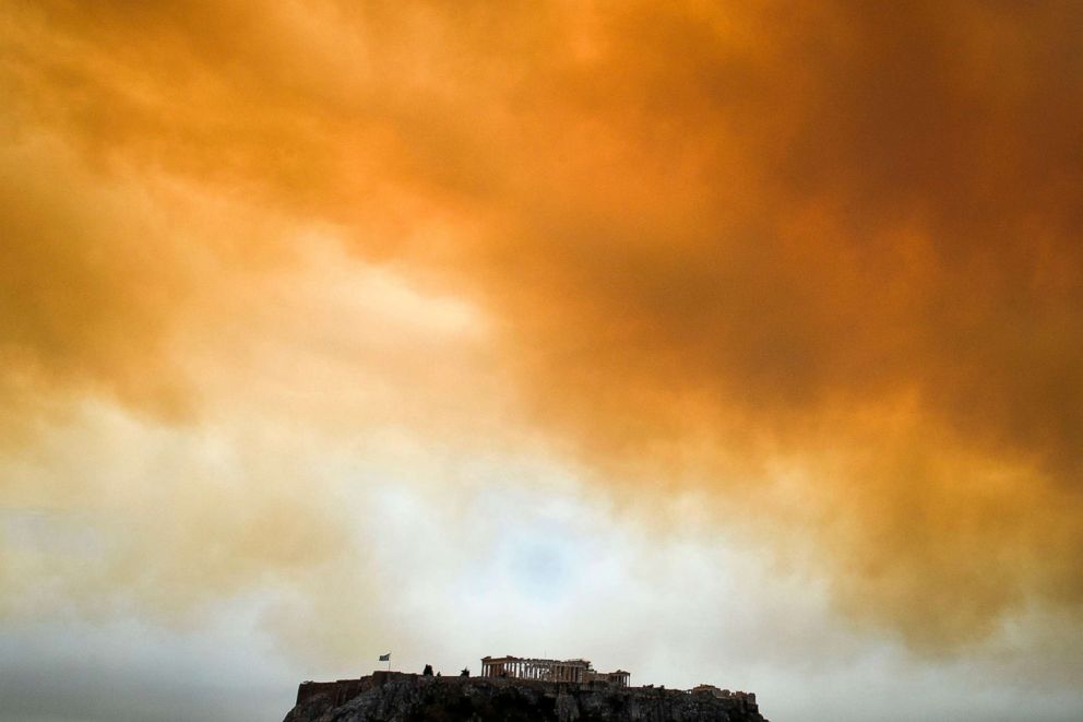PHOTO: The Parthenon temple on the Acropolis hill in Athens is seen as smoke billows in background during a wildfire in Kineta, near Athens.