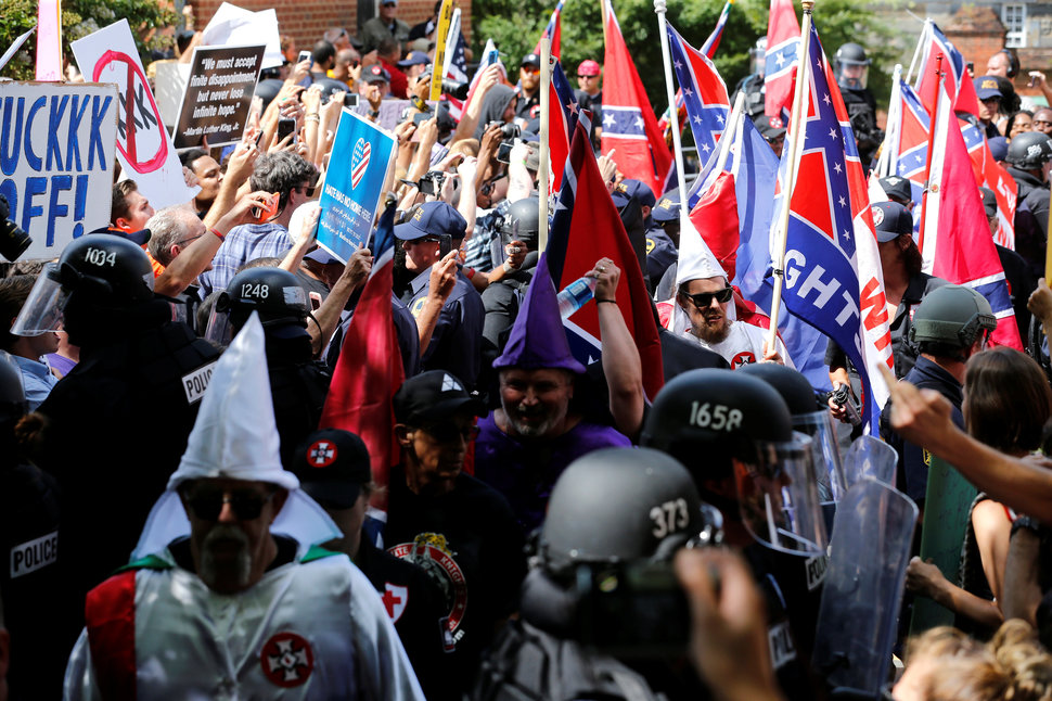 Riot police protect members of the Ku Klux Klan from counter-protesters as they arrive to rally in support of Confederate mon