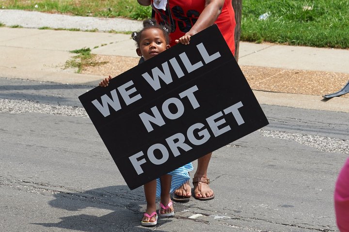 A young girl holds a sign on Aug. 8, 2015, in Ferguson, Missouri, a year after the police shooting death of Michael Brown Jr.