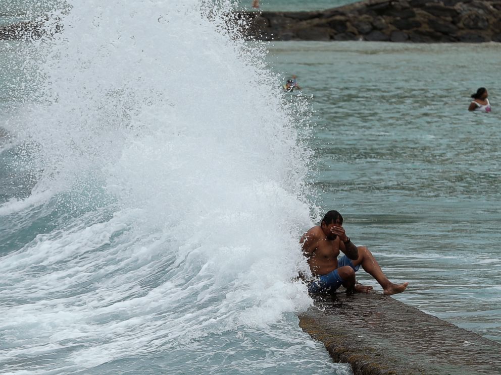 A large wave hits a man on a breakwater along Waikiki Beach ahead of Hurricane Lane, Friday, Aug. 24, 2018, in Honolulu.