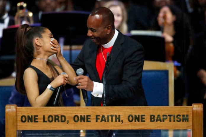 Ariana Grande, left, laughs with Bishop Charles H. Ellis during the funeral service for Aretha Franklin at Greater Grace Temple, Friday, Aug. 31, 2018, in Detroit. Franklin died Aug. 16, 2018 of pancreatic cancer at the age of 76. (AP Photo/Paul Sancya)
