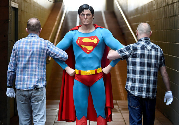 Prop Store employees with a Superman costume worn by Christopher Reeve from the 1978 and 1980 films.
