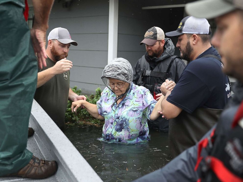 PHOTO: Volunteer rescuer workers help a woman from her home that was inundated with the flooding of Hurricane Harvey on Aug. 30, 2017 in Port Arthur, Texas.
