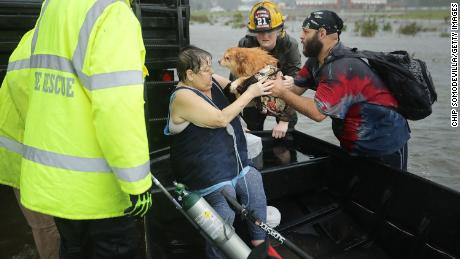 In James City, North Carolina, rescuers help a woman and her dog from their flooded home on Friday.