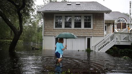 Kim Adams wades through floodwaters surrounding her home Saturday in Southport, North Carolina.
