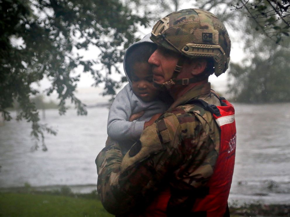 PHOTO: Rescue team member Sgt. Nick Muhar, from the North Carolina National Guard 1/120th battalion, evacuates a young child as the rising floodwaters from Hurricane Florence threatens his home in New Bern, N.C., on Friday, Sept. 14, 2018.