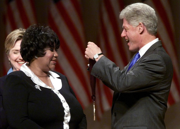 President Bill Clinton awards singer Aretha Franklin with a National Medal of the Arts in 1999 as first lady Hillary Clinton 