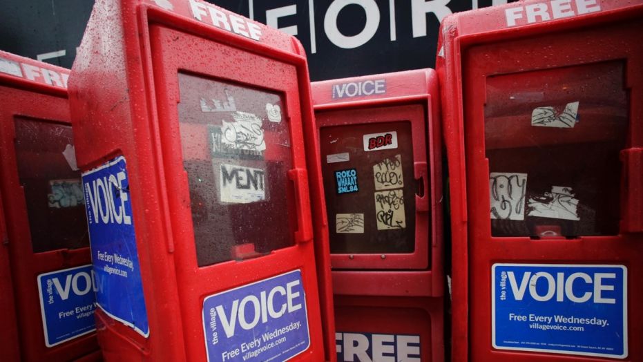 In this Nov. 27, 2013 photo, plastic newspaper boxes for The Village Voice stand along a Manhattan sidewalk in New York. 