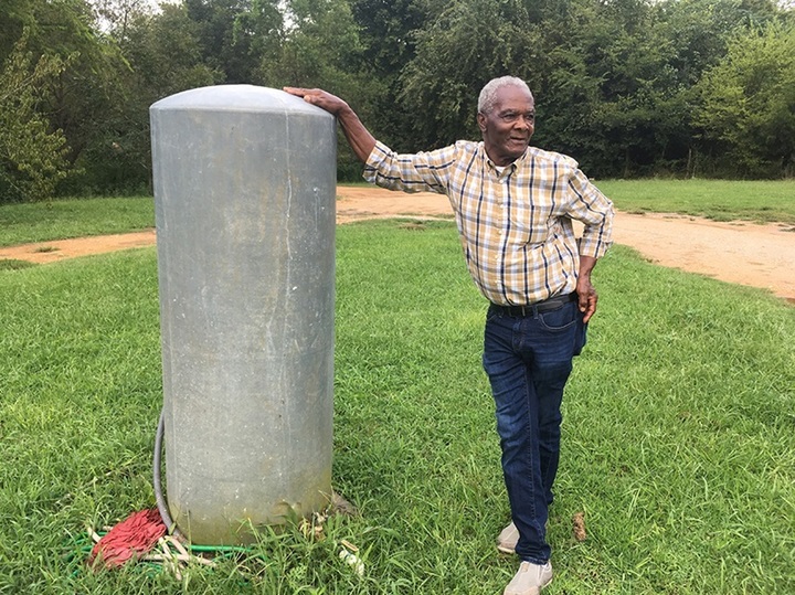 Booker Gipson leans against the tank his family uses for water. The 77-year-old grandfather is concerned the landfill across 
