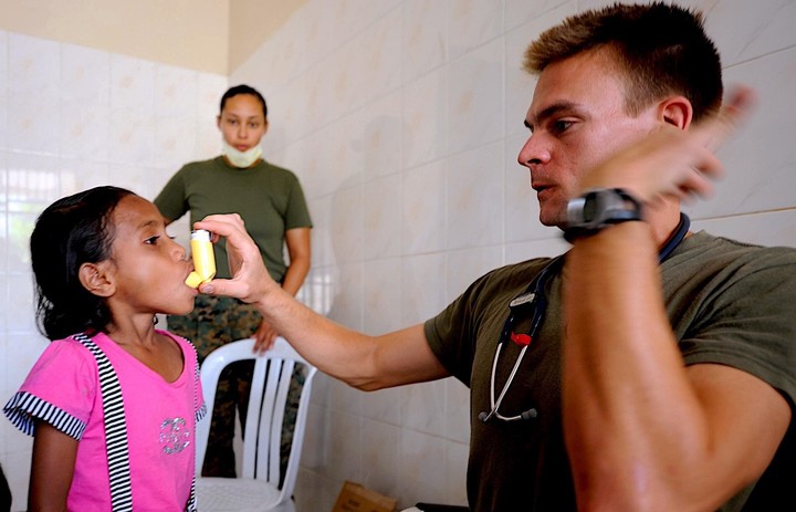 Lt. Brandon Van Noord shows a girl how to use an inhaler at a clinic.