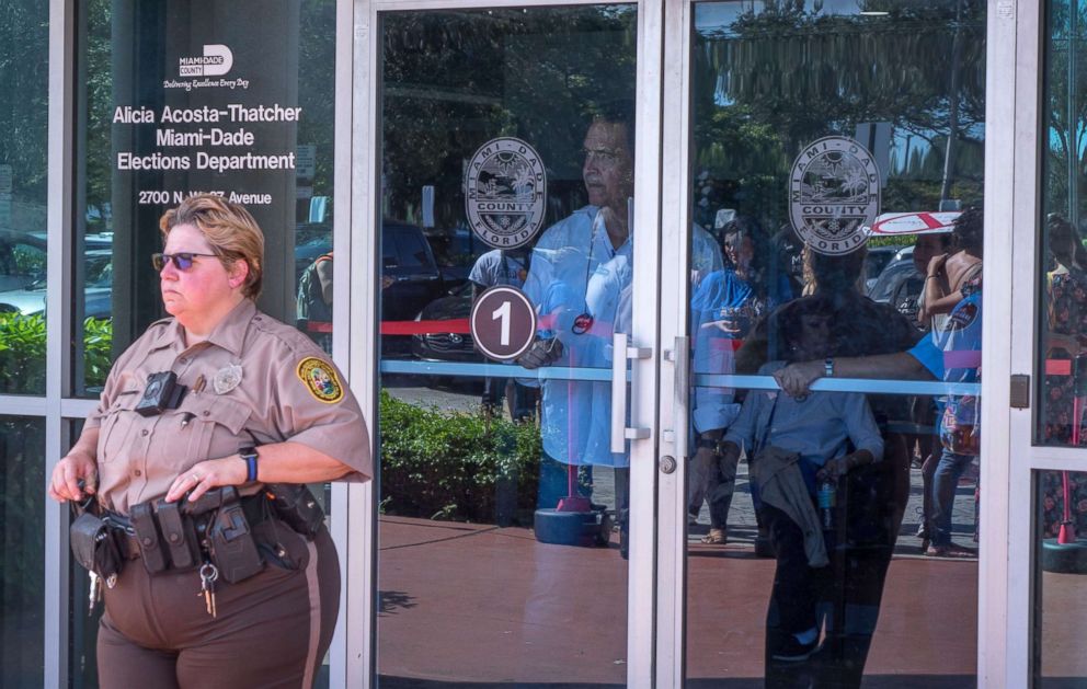 PHOTO: A police officer guards the entrance of the Miami-Dade Election Department while a crowd protests to demand the vote recount outside this facility in Miami, Nov. 10, 2018.