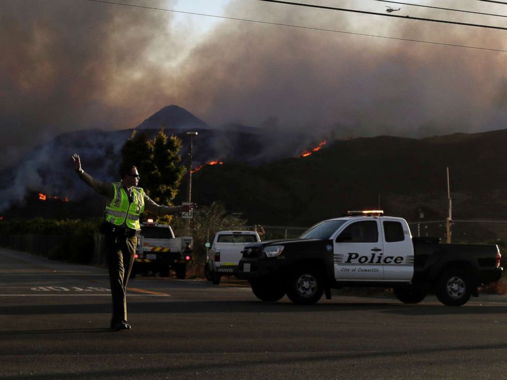 PHOTO: A police officer mans a checkpoint in front of an advancing wildfire Thursday, Nov. 8, 2018, near Newbury Park, Calif.