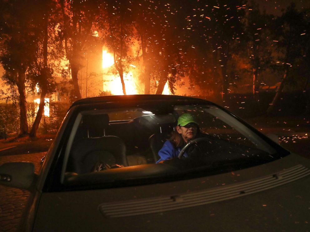 PHOTO: Tina Weeks jumps into her car to evacuate after her neighbors house became fully engulfed by the Woolsey Fire in Oak Park, Ca., in the early morning of Nov. 9, 2018.