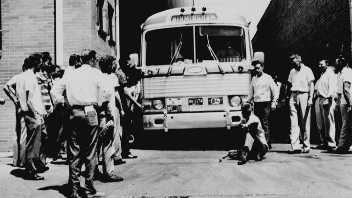 An unidentified white man sits in front of a Greyhound bus to prevent it from leaving the station with a load of Freedom Ride