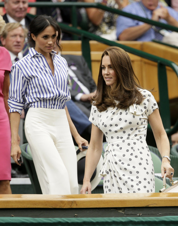 Kate, Duchess of Cambridge and Meghan, Duchess of Sussex, left, take their seats in the Royal Box on Centre Court at the Wimb