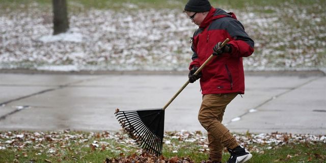 Kaleb Klakulak raking leaves in Rochester Hills, Mich., as he raises money for a headstone for his best friend Kenneth "K.J." Gross, who died of cancer last year. (Max Ortiz/Detroit News via AP)