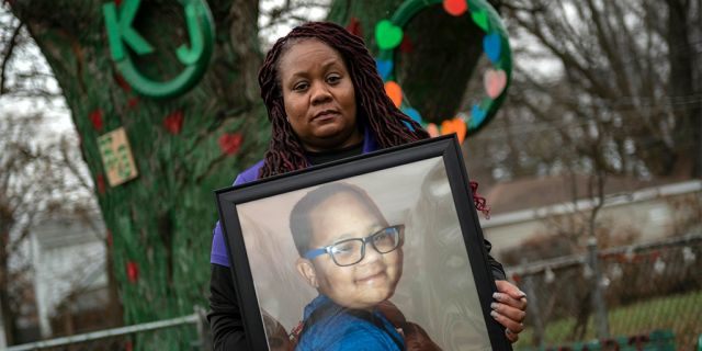 LaSondra Singleton holding a photo of her son Kenneth Gross Jr. while standing in front of a tree that was decorated in the child's honor at her Warren, Mich., home. Kenneth died at age 12 waiting for a donor heart that failed due to complications from cancer. (David Guralnick/Detroit News via AP)