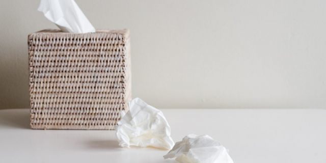 Rattan tissue box and crumpled tissues on table - cold and flu season concept, grief concept (selective focus)