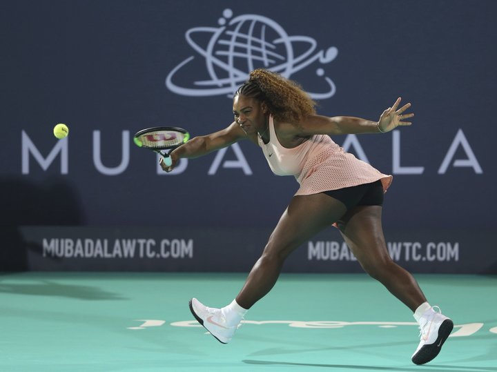Serena Williams returns the ball to her sister Venus during a match at the opening day of the Mubadala World Tennis Champions