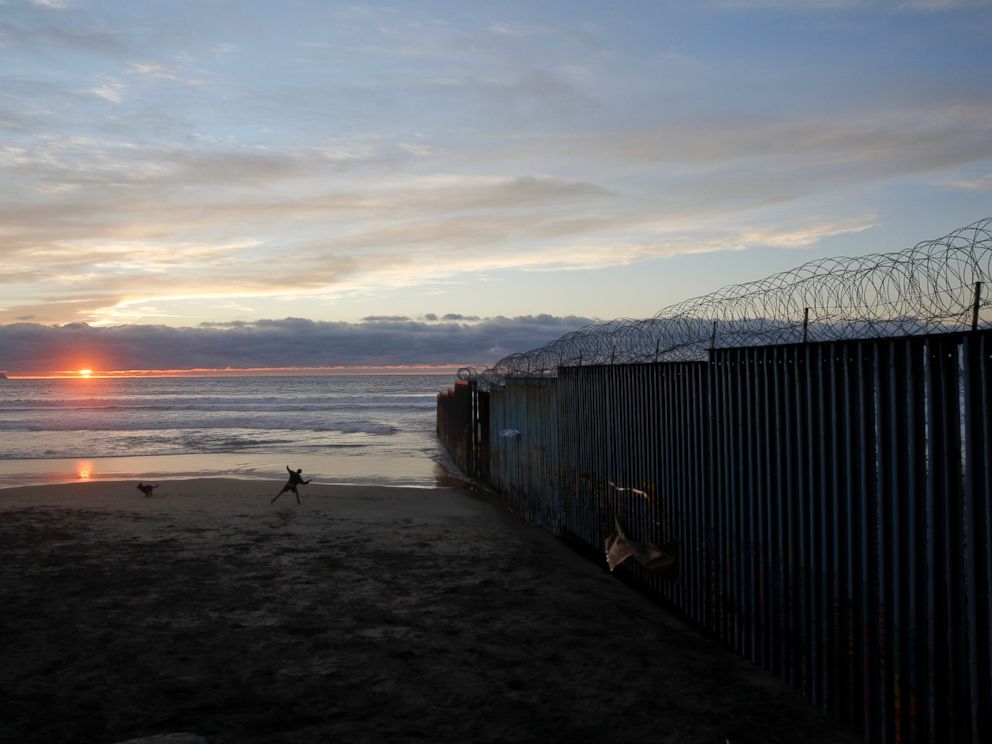 PHOTO: In this Jan. 9, 2019, file photo, a man throws a ball for his dog next to the border wall topped with razor wire in Tijuana, Mexico. 