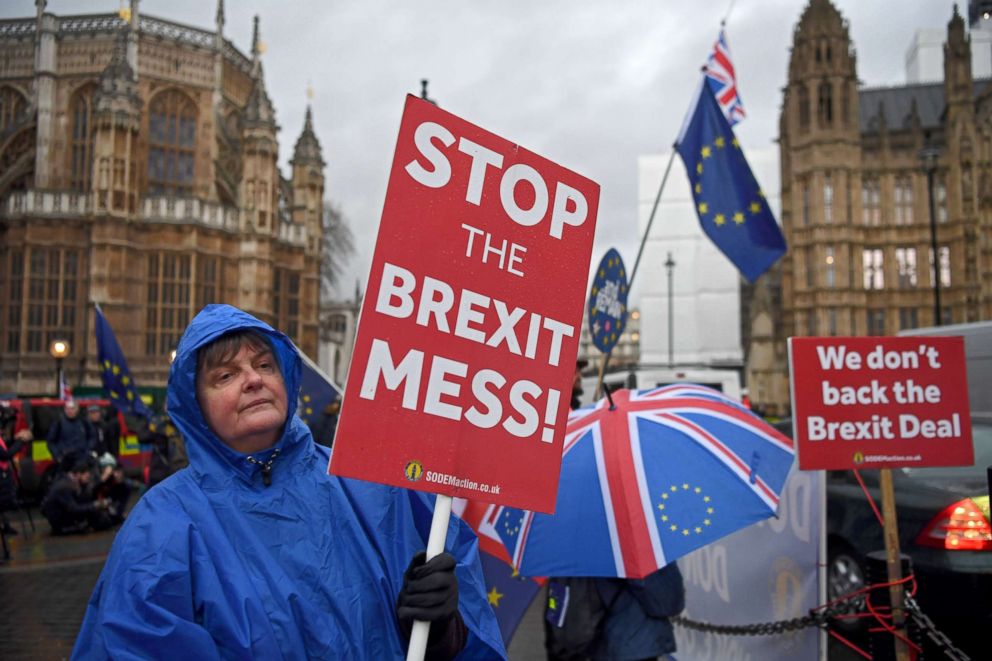 PHOTO: Brexit protesters shelter from a rain shower outside the houses of parliament in London, Jan. 16, 2019.