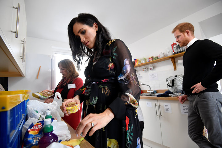 Meghan and Prince Harry in the One25 kitchen with a volunteer.