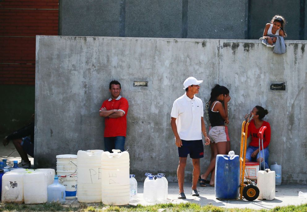 PHOTO: People wait in line to fill up containers with water from a public fountain in Caracas, Venezuela, March 12, 2019.