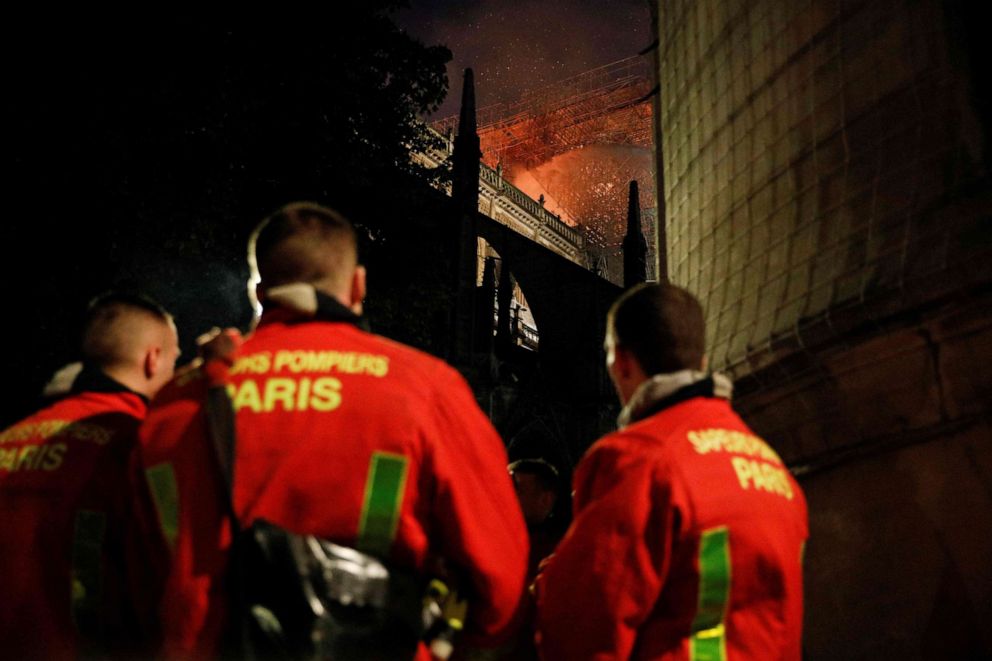 Firefighters watch the flames billowing from the roof at Notre Dame Cathedral in Paris on April 15, 2019.