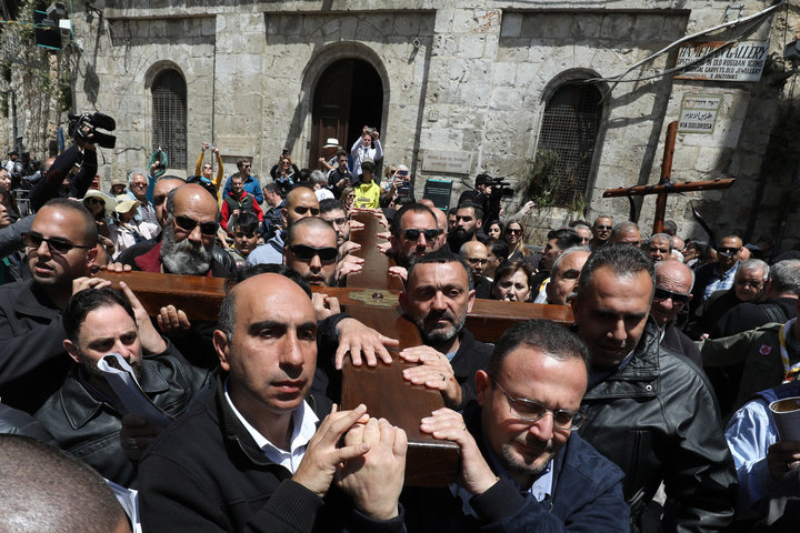 Members of a local Catholic Palestinian parish carry a wooden cross along the Via Dolorosa (Way of Suffering) in Jerusalem's 