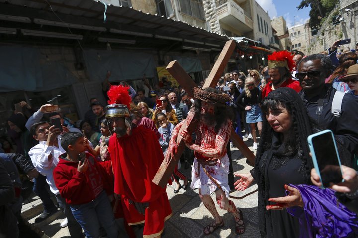 An actor carries a cross toward the Church of the Holy Sepulchre, traditionally believed to be the site of the crucifixion of