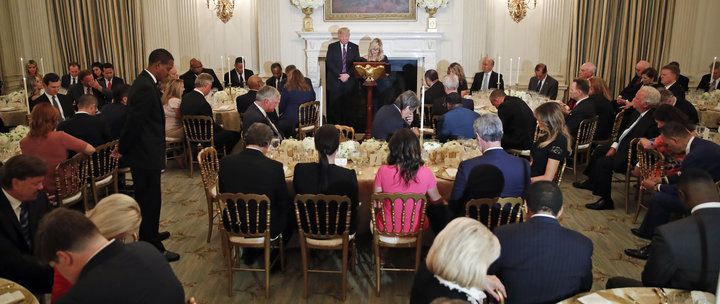 President Donald Trump bows his head as his spiritual adviser Paula White prays during an Aug. 27, 2018, dinner for evangelic