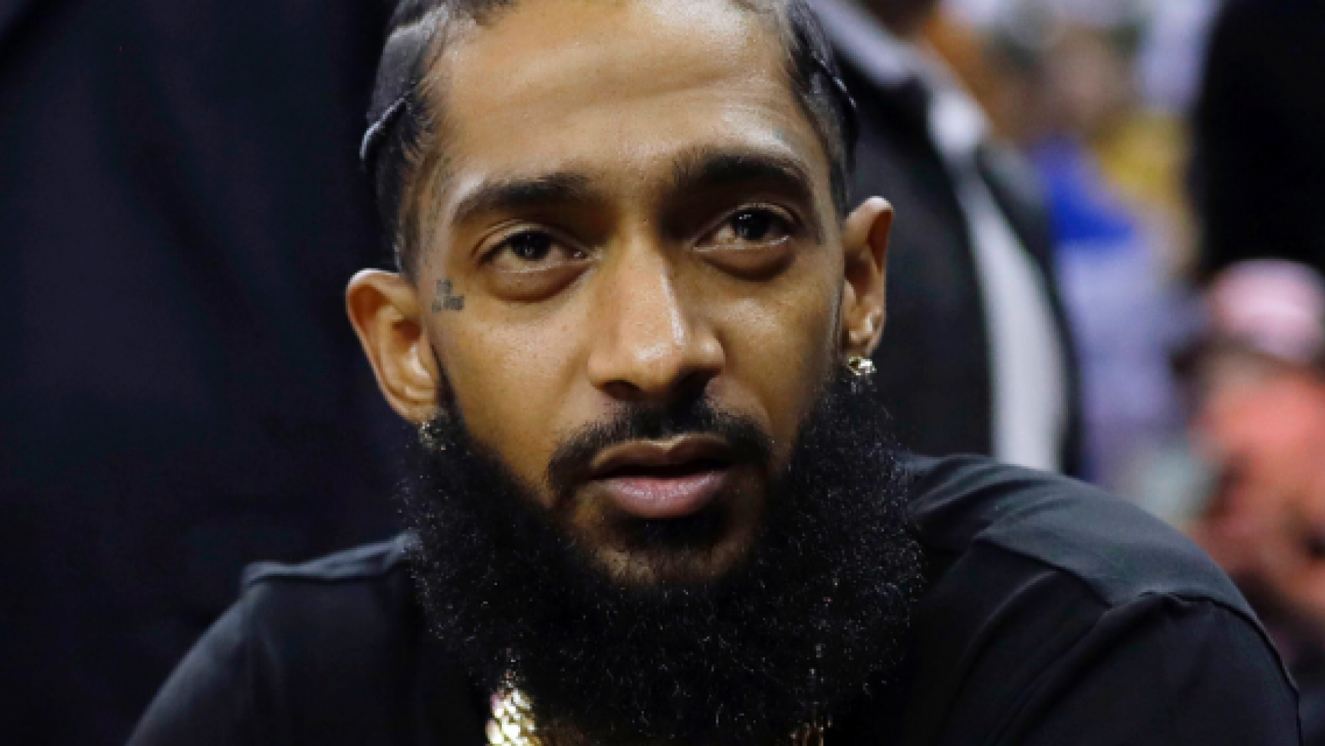 This March 29 file photo shows rapper Nipsey Hussle at an NBA  game between the Golden State Warriors and the Milwaukee Bucks in Oakland. Hussle was shot and killed on Sunday outside  his clothing store in Los Angeles. (AP Photo/Marcio Jose Sanchez, File)