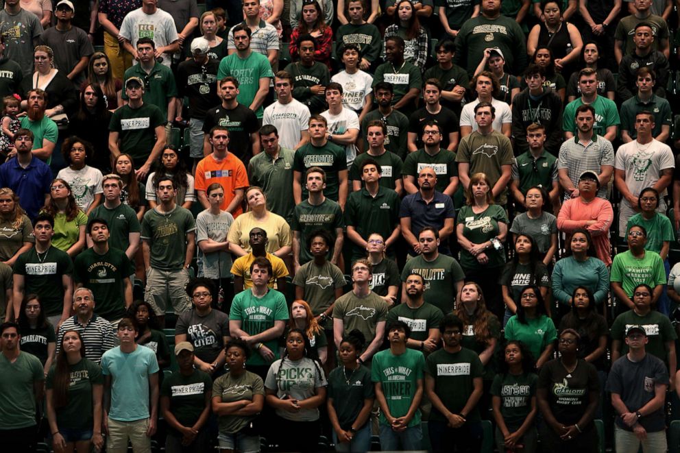 PHOTO: People stand during a vigil in the Dale F. Halton Arena at University of North Carolina at Charlotte campus the day after a gunman opened fire on students, May 1, 2019.